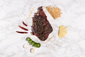 above shot of beef jerky showing jalapeños, peppers, and other spices involved in the making process of our jerky